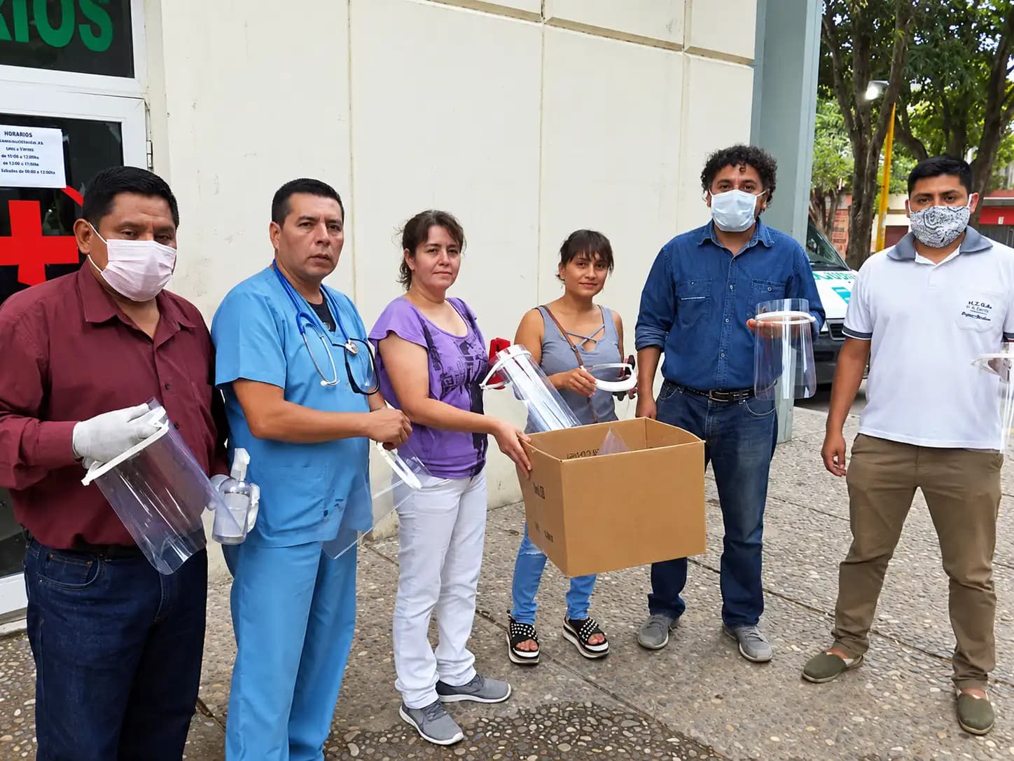 Docentes y personal de salud frente al hospital con las máscaras de protección facial impresas en 3D