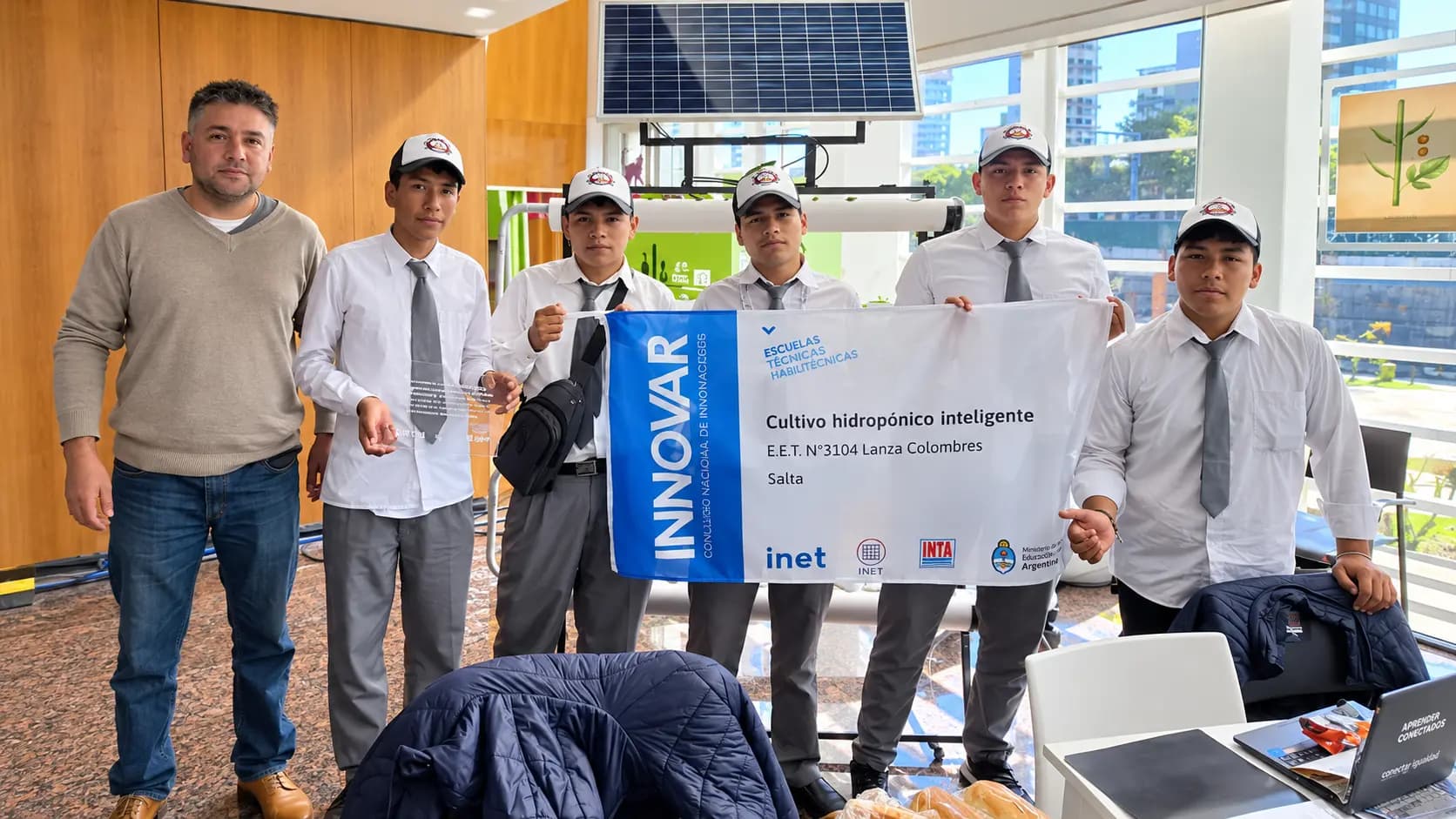 Alumnos y un docente con la bandera de INNOVAR del proyecto Cultivo hidropónico inteligente